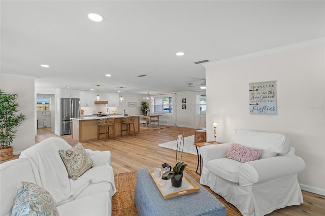 living area featuring light wood-style floors, recessed lighting, and crown molding