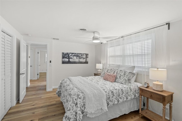 bedroom featuring visible vents, ceiling fan, baseboards, and wood finished floors