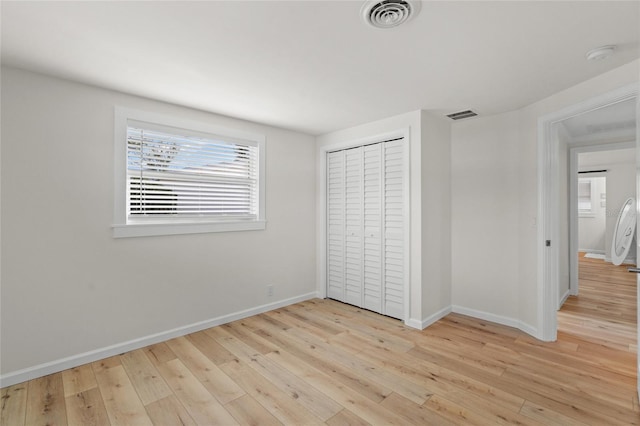 unfurnished bedroom featuring light wood finished floors, visible vents, and baseboards