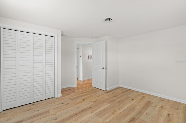 unfurnished bedroom with light wood-style floors, visible vents, baseboards, and a closet