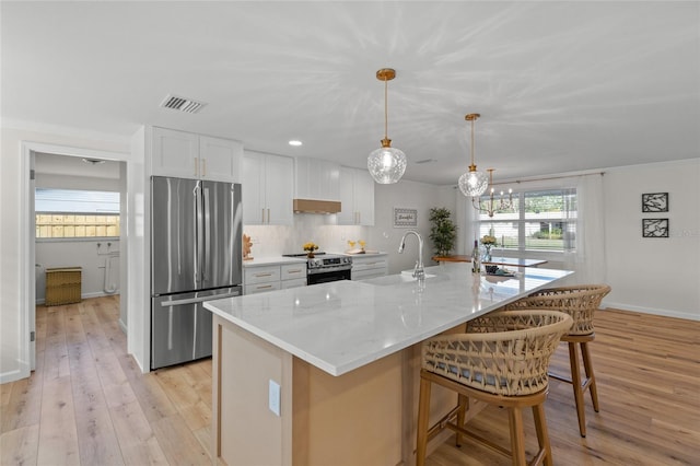 kitchen with a center island with sink, appliances with stainless steel finishes, white cabinetry, pendant lighting, and a sink