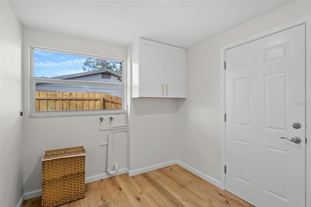 laundry room featuring cabinet space, baseboards, and light wood-style floors