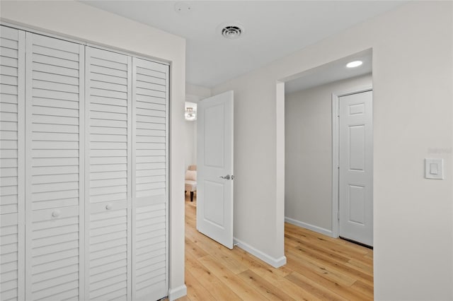 hall with light wood-style floors, baseboards, and visible vents