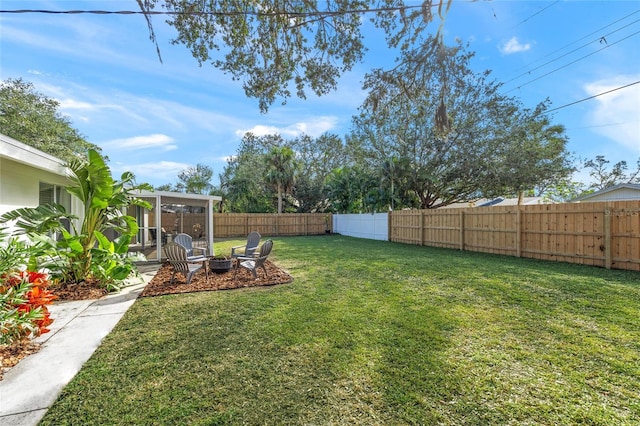 view of yard with a fenced backyard and a fire pit