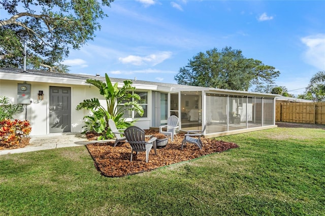 rear view of property with a yard, a sunroom, fence, and stucco siding