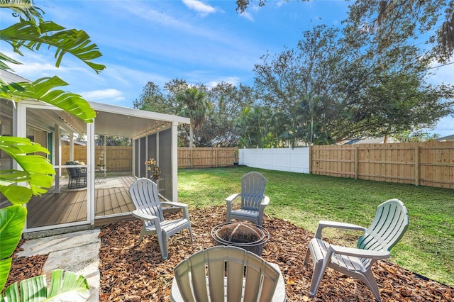 view of yard featuring an outdoor fire pit, a fenced backyard, and a wooden deck