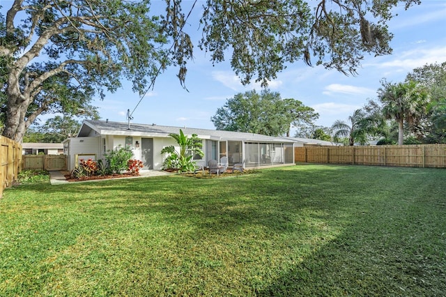 rear view of property featuring a sunroom, a fenced backyard, and a lawn