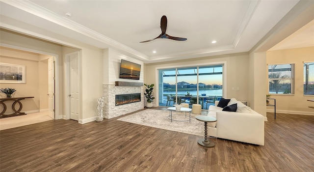 living room featuring ornamental molding, dark hardwood / wood-style flooring, and a stone fireplace