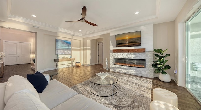 living room featuring crown molding, ceiling fan, a tray ceiling, and dark wood-type flooring