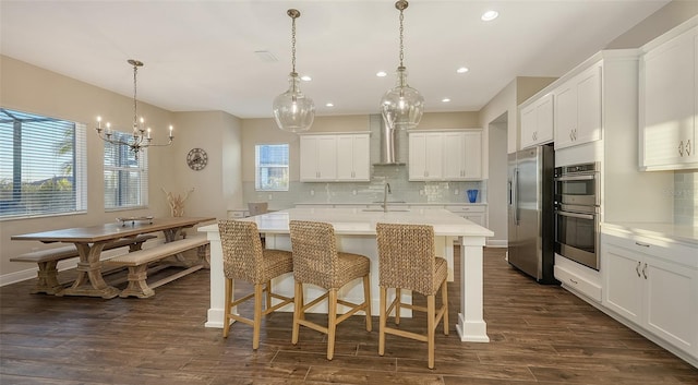 kitchen with pendant lighting, stainless steel appliances, sink, and white cabinets