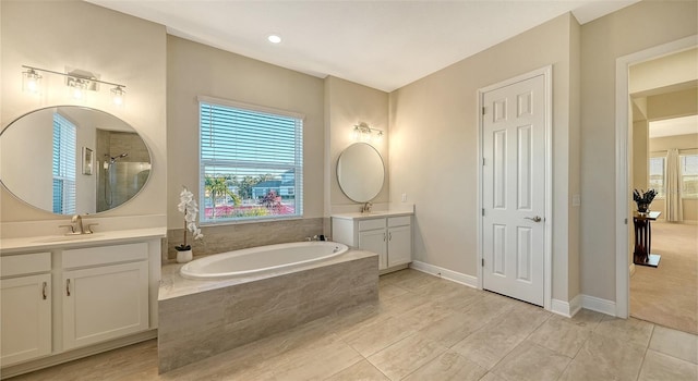 bathroom featuring vanity, tiled tub, and a wealth of natural light