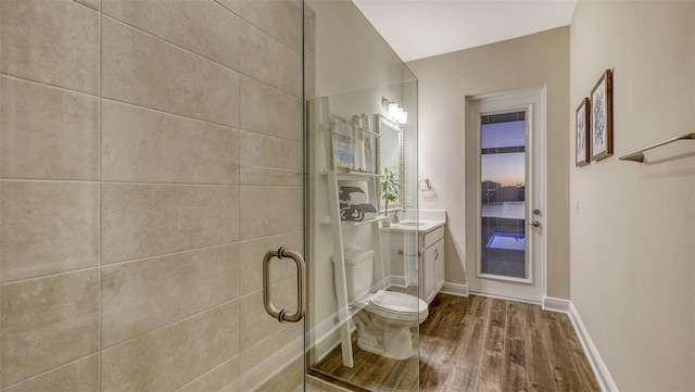 bathroom featuring vanity, toilet, a shower with shower door, and hardwood / wood-style floors