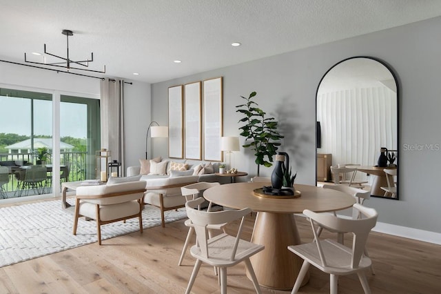 interior space with a notable chandelier, light hardwood / wood-style flooring, and a textured ceiling