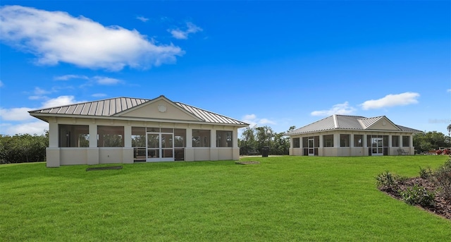 rear view of property featuring a sunroom and a lawn