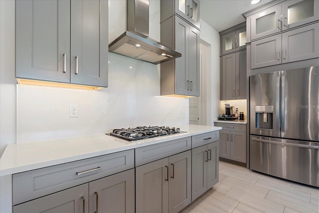 kitchen with gray cabinetry, gas cooktop, exhaust hood, and stainless steel refrigerator with ice dispenser