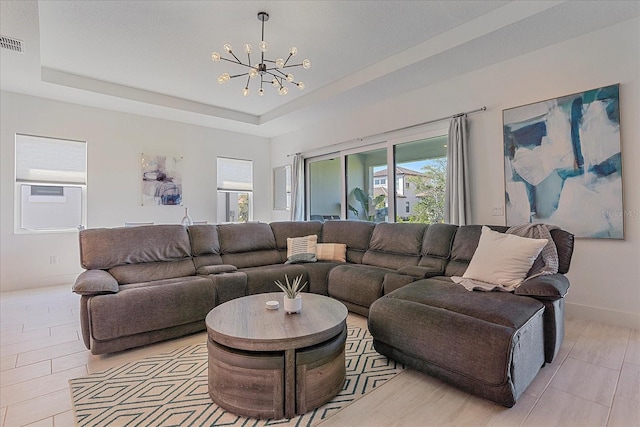 living room featuring a raised ceiling, light tile patterned floors, and a notable chandelier