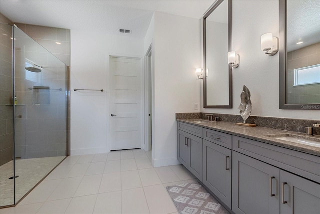 bathroom with tile patterned flooring, vanity, a textured ceiling, and a tile shower