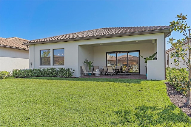 back of property with a yard and a patio area