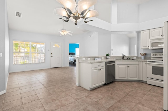 kitchen featuring sink, white appliances, white cabinetry, ceiling fan with notable chandelier, and kitchen peninsula