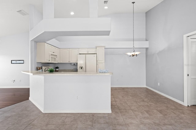 kitchen featuring a towering ceiling, an inviting chandelier, white appliances, and decorative light fixtures