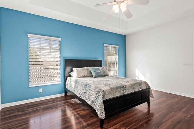 bedroom featuring dark wood-type flooring, ceiling fan, and a tray ceiling