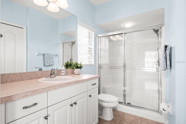 bathroom featuring tile patterned floors, vanity, toilet, and a shower with shower door