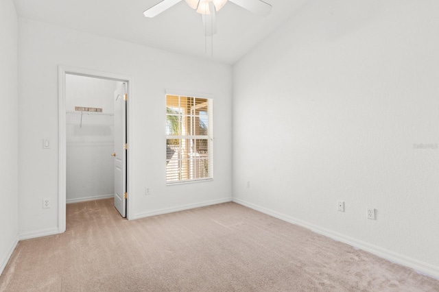 unfurnished bedroom with a walk in closet, light colored carpet, a closet, and ceiling fan