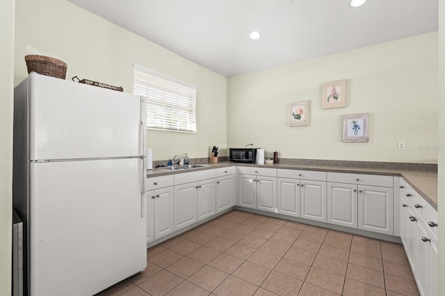 kitchen with sink, light tile patterned flooring, white cabinets, and white fridge