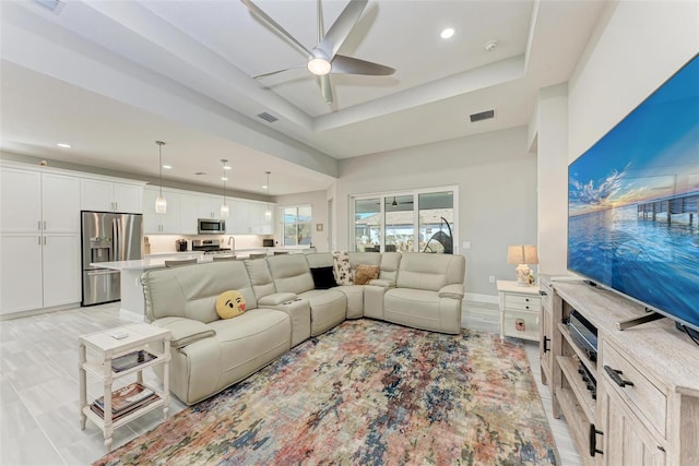 living room featuring a tray ceiling and ceiling fan