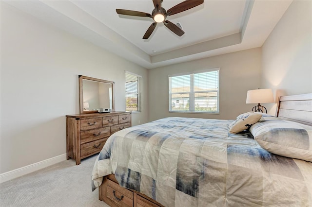 carpeted bedroom featuring ceiling fan and a tray ceiling