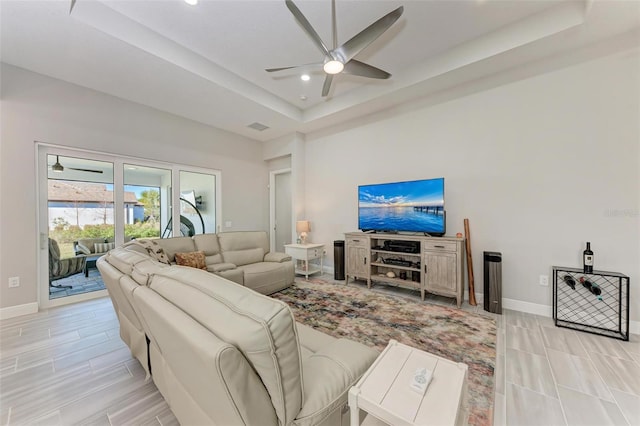 living room with ceiling fan and a raised ceiling