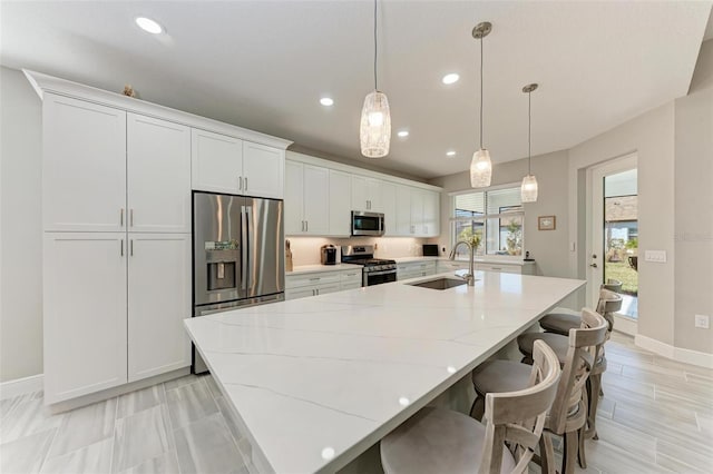 kitchen with a spacious island, sink, white cabinetry, hanging light fixtures, and stainless steel appliances