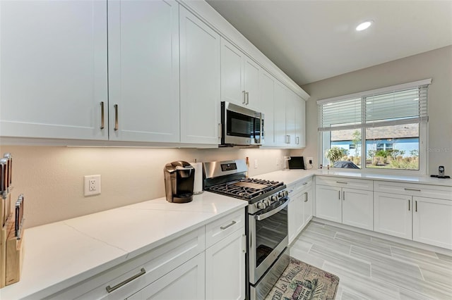 kitchen with white cabinetry, light stone counters, and appliances with stainless steel finishes