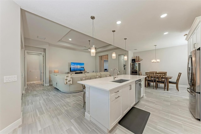 kitchen with white cabinetry, appliances with stainless steel finishes, sink, and a kitchen island with sink