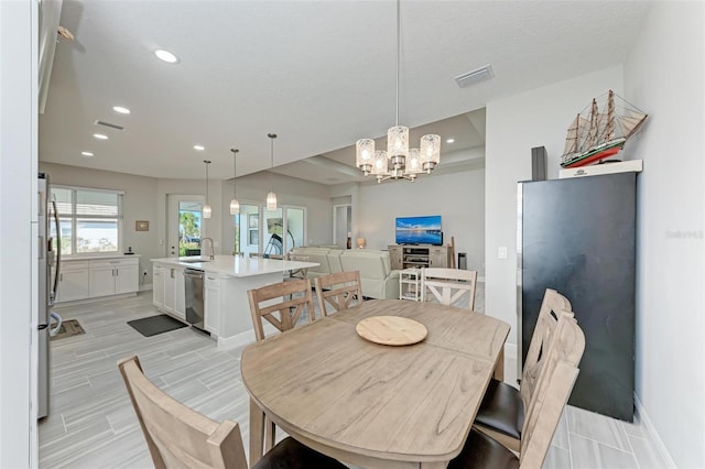 dining area featuring sink, a textured ceiling, and an inviting chandelier