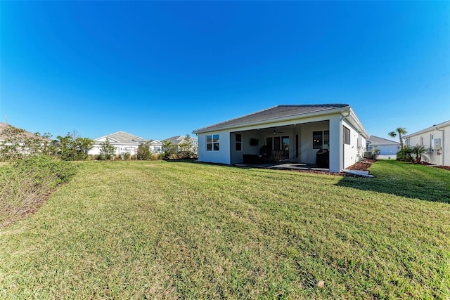 rear view of property featuring a patio, ceiling fan, and a lawn