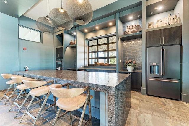 kitchen with dark brown cabinets, high quality fridge, pendant lighting, and a breakfast bar