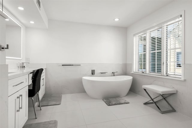 bathroom featuring tile walls, vanity, tile patterned flooring, and a tub