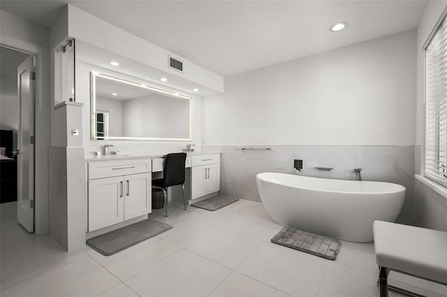 bathroom with vanity, a tub to relax in, tile patterned floors, and tile walls