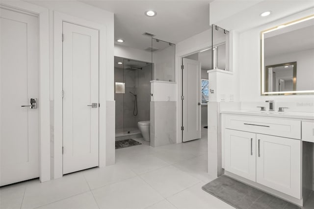 bathroom featuring vanity, toilet, tile patterned flooring, and a shower with door