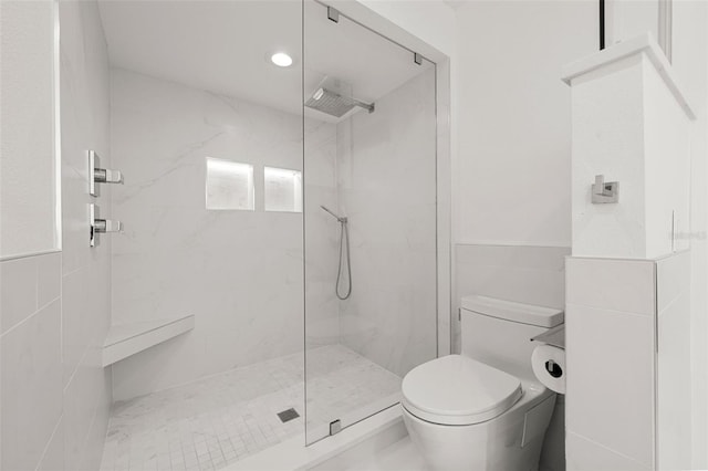 bathroom featuring tiled shower, tile walls, and toilet