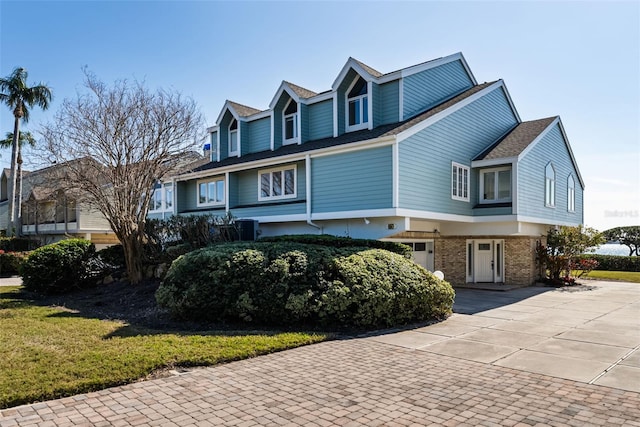 view of front of home featuring a garage, a front lawn, and central air condition unit