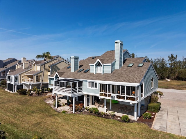 back of property with a lawn, a sunroom, and a patio