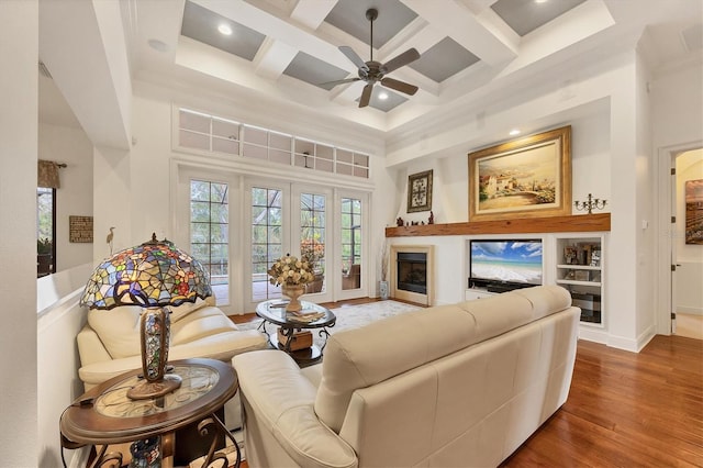 living room featuring coffered ceiling, crown molding, wood-type flooring, beamed ceiling, and a high ceiling