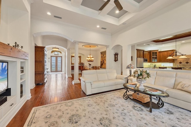 living room with coffered ceiling, crown molding, ceiling fan with notable chandelier, and decorative columns