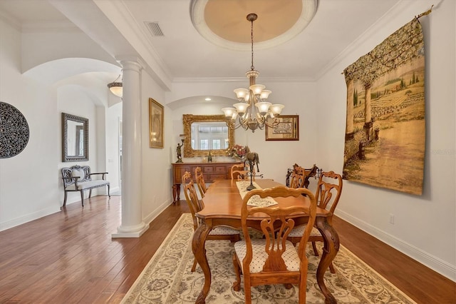 dining area with decorative columns, ornamental molding, dark hardwood / wood-style flooring, and a tray ceiling