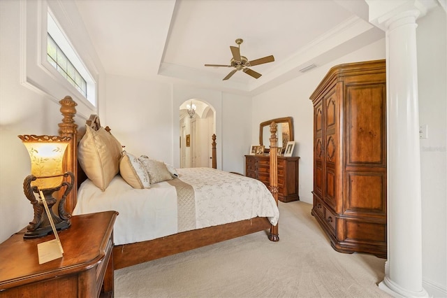 bedroom with decorative columns, light colored carpet, ceiling fan, and a tray ceiling