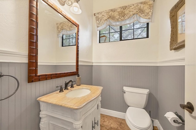 bathroom with tile patterned flooring, vanity, wood walls, and toilet