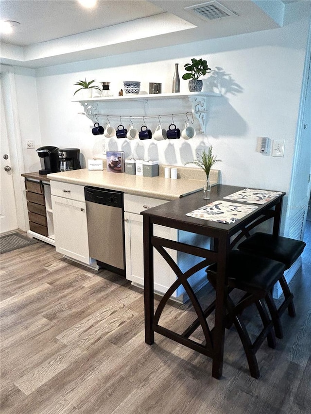 bar featuring white cabinetry, dishwasher, hardwood / wood-style floors, and a raised ceiling