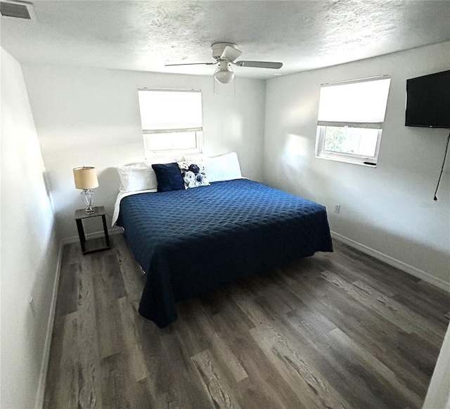 bedroom with ceiling fan, dark hardwood / wood-style floors, and a textured ceiling